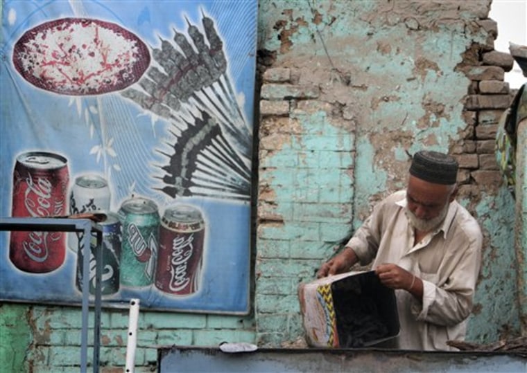 An Afghan man prepares coal to make a fire for cooking, outside of a local restaurant, in Kabul.